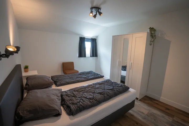 Slaapkamer met tweepersoonsbed en witte kledingkast