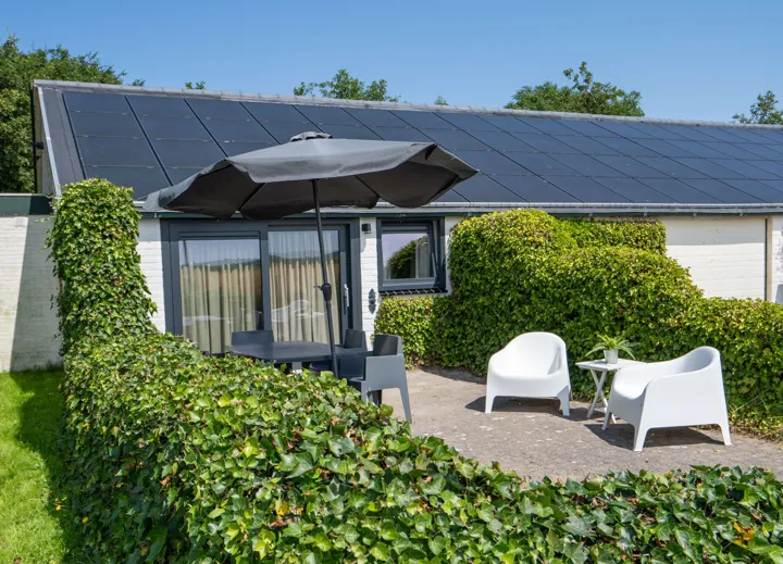 Terras voor de woning met loungestoelen en parasol