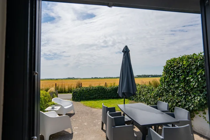 Door de open schuifpui uitzicht op het terras en de weilanden