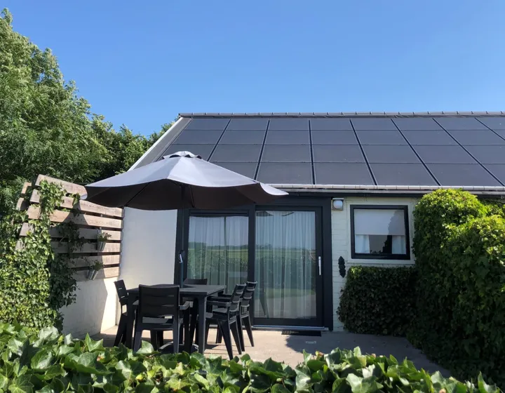 De woning met zonnepanelen op het dak en het terras ervoor
